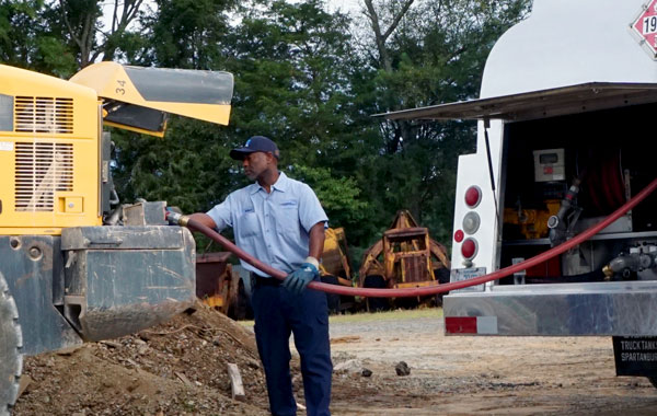 man pumping fuel into construction vehicle