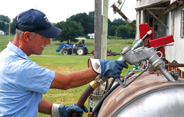 man filling fuel tank for farming